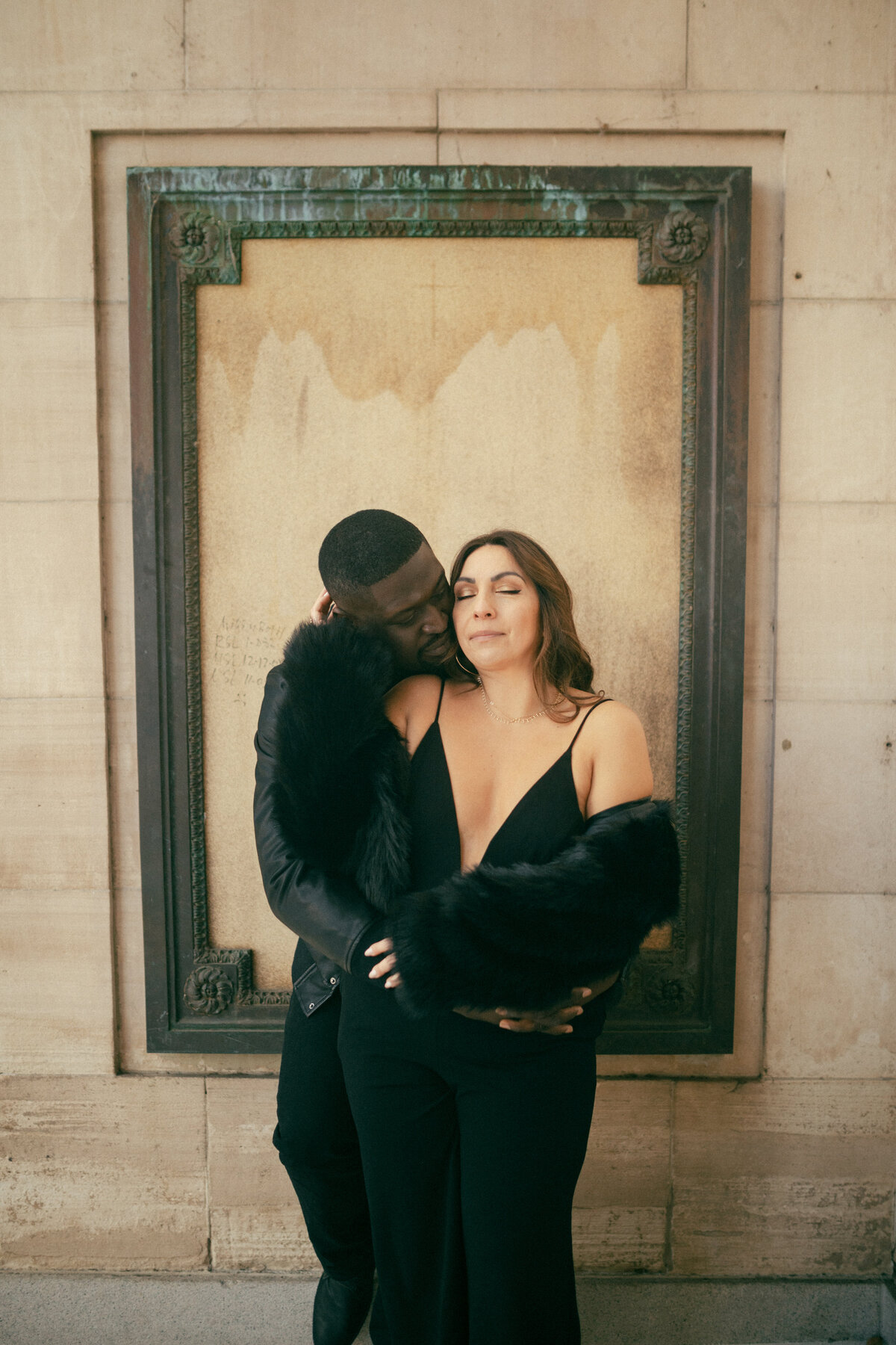 Man and woman holding each other with eyes closed during reno nevada downtown engagement session wearing black in front of a frame at courthouse