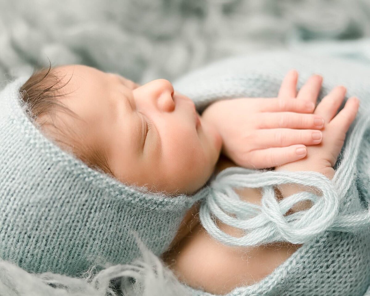 baby boy in blue sleeping with hands out
