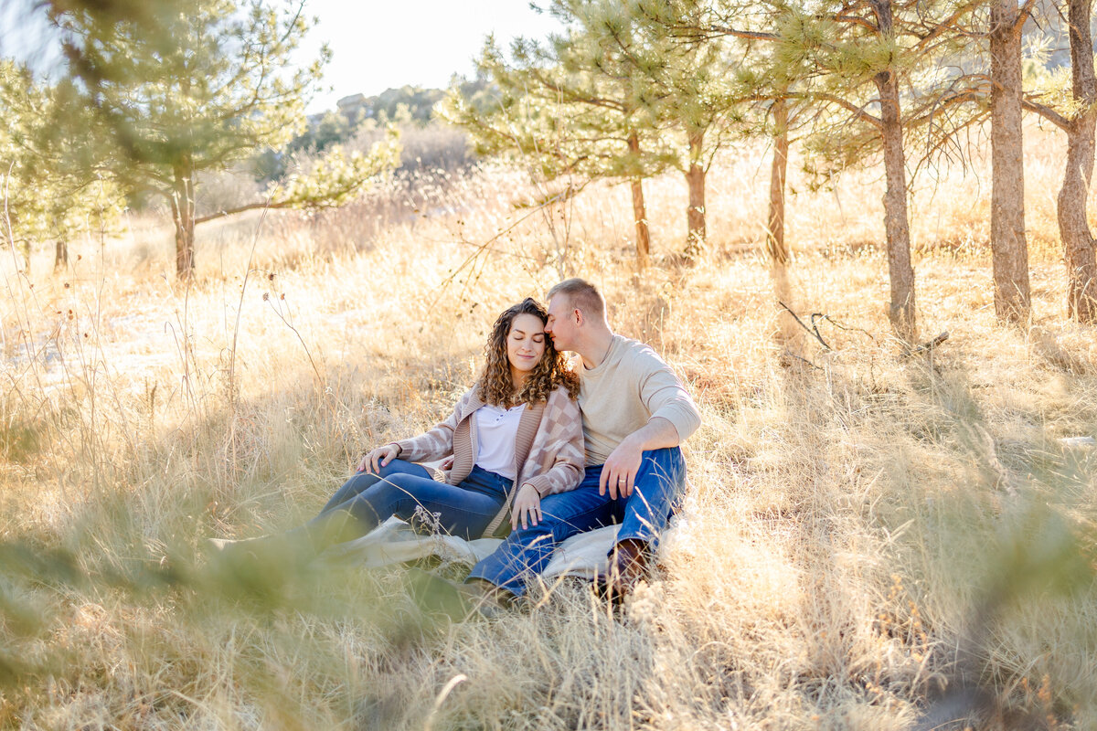 Colorado Springs Family Photographer- couple sitting in a field lovingly