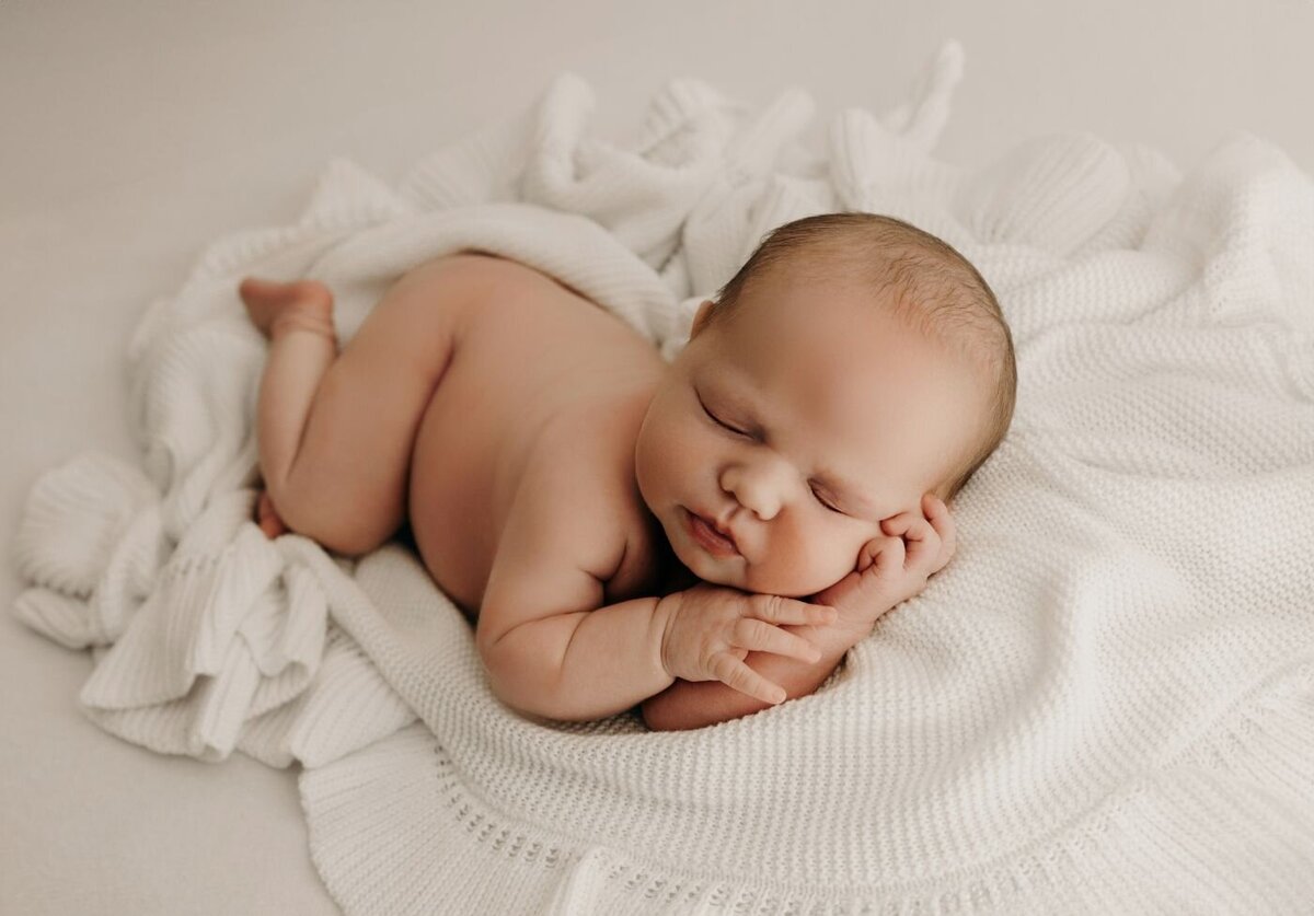 Tranquil portrait of a sleeping newborn baby lying on a fluffy white blanket, captured by a Mullingar newborn photographer
