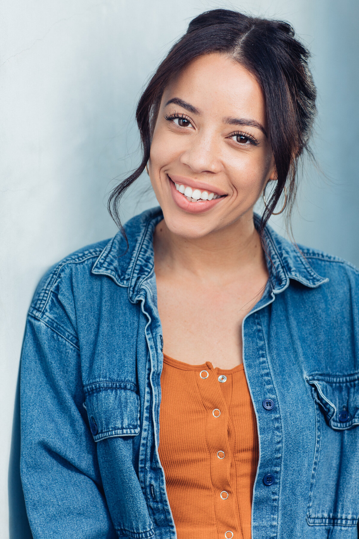 Headshot Photograph Of Young Woman In Outer Blue Denim Jacket And Inner Orange Buttoned Shirt Los Angeles