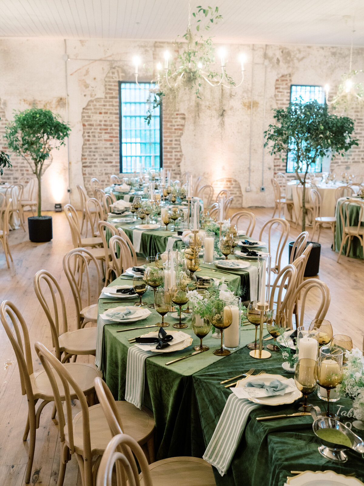 A beautifully arranged wedding reception table adorned with green accents, elegant tableware, and an artistic centerpiece, creating an inviting and romantic atmosphere at Twenty-One Magazine.