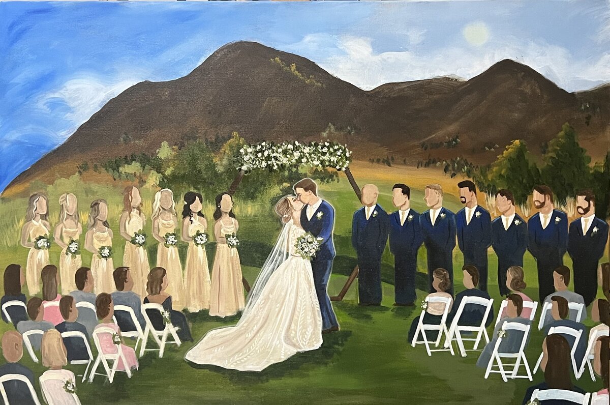A couple is painting during their first kiss in Colorado with the audience and bridal party looking