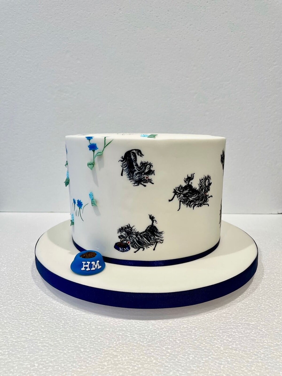 A birthday cake with hand painted dogs all over and a little model dog bowl