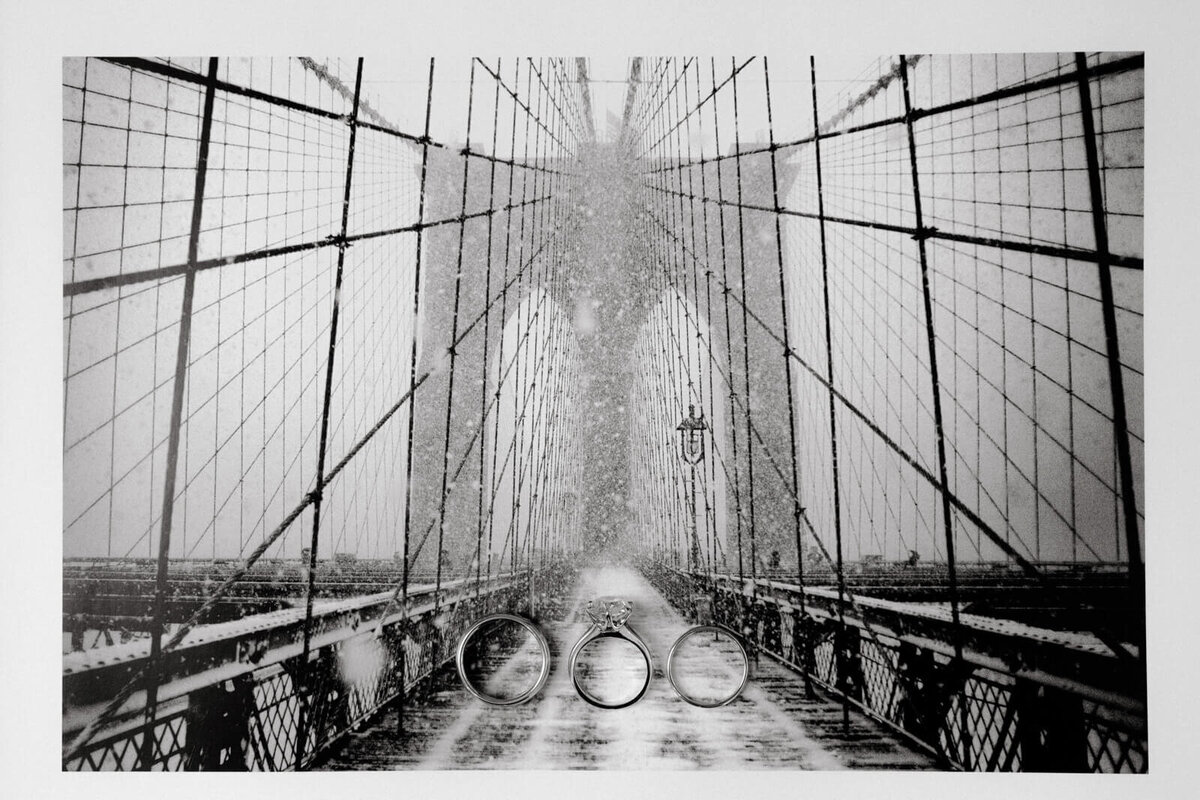 A photo of a black and white picture of Brooklyn bridge, with three rings on top of the photo