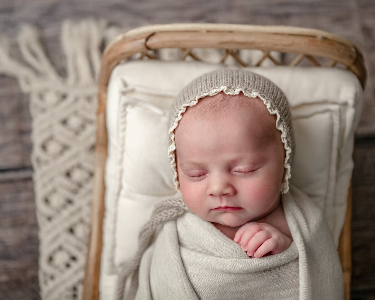 newborn girl wearing neutral bonnet