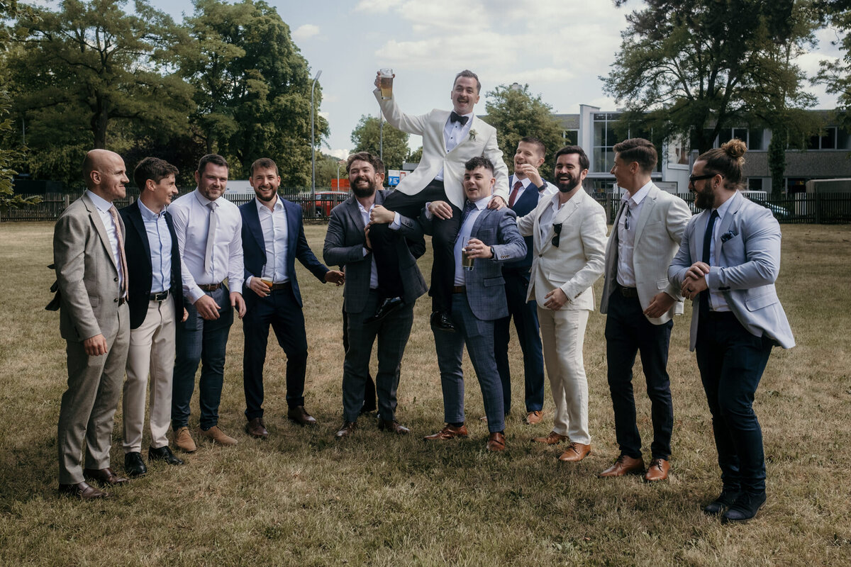 Der Bräutigam wird auf diesem Gruppenfoto mit seinen Freunden auf den Schultern getragen.