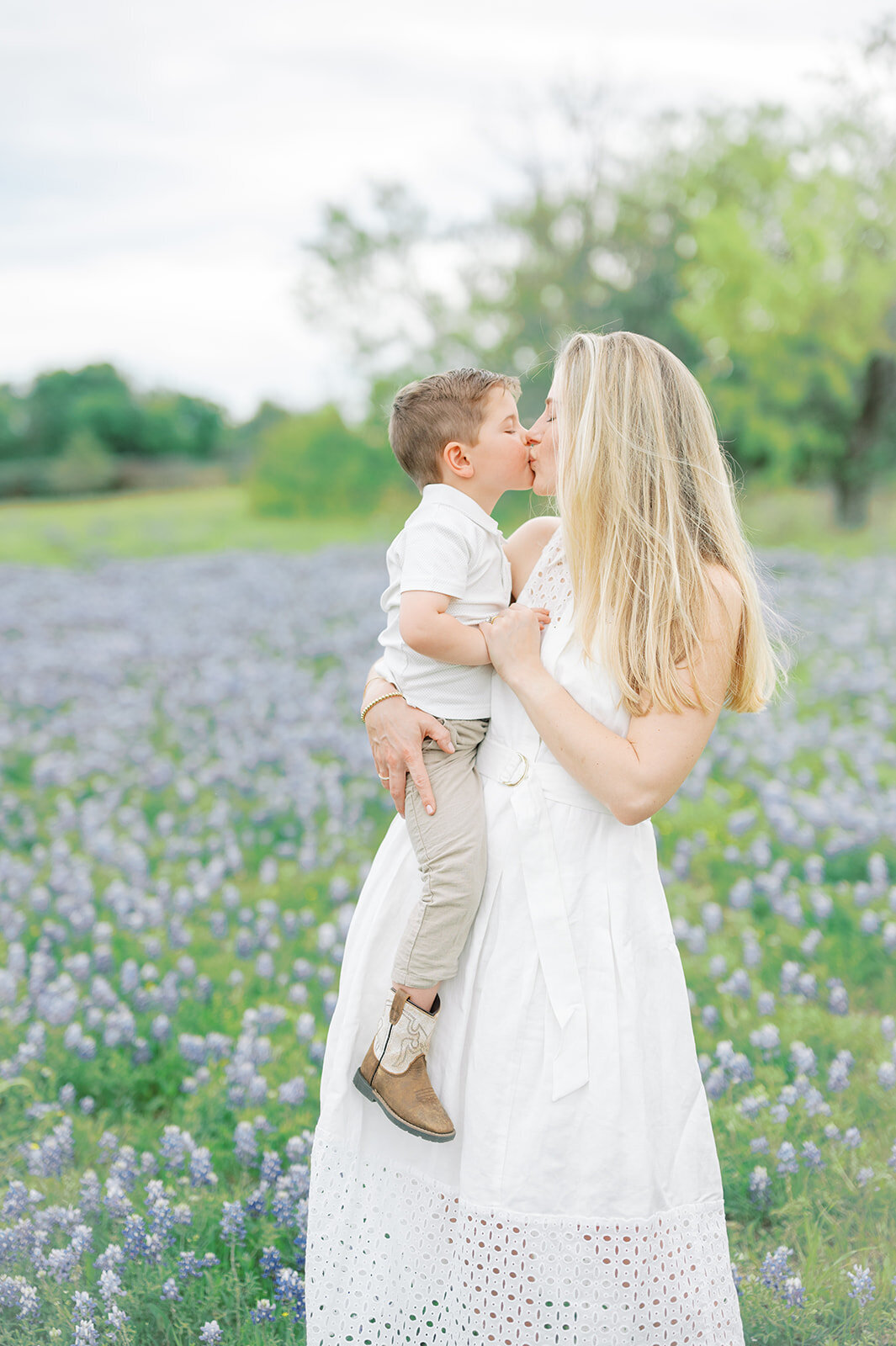 Mother kissing son in a field of bluebonnets in Dallas, Texas