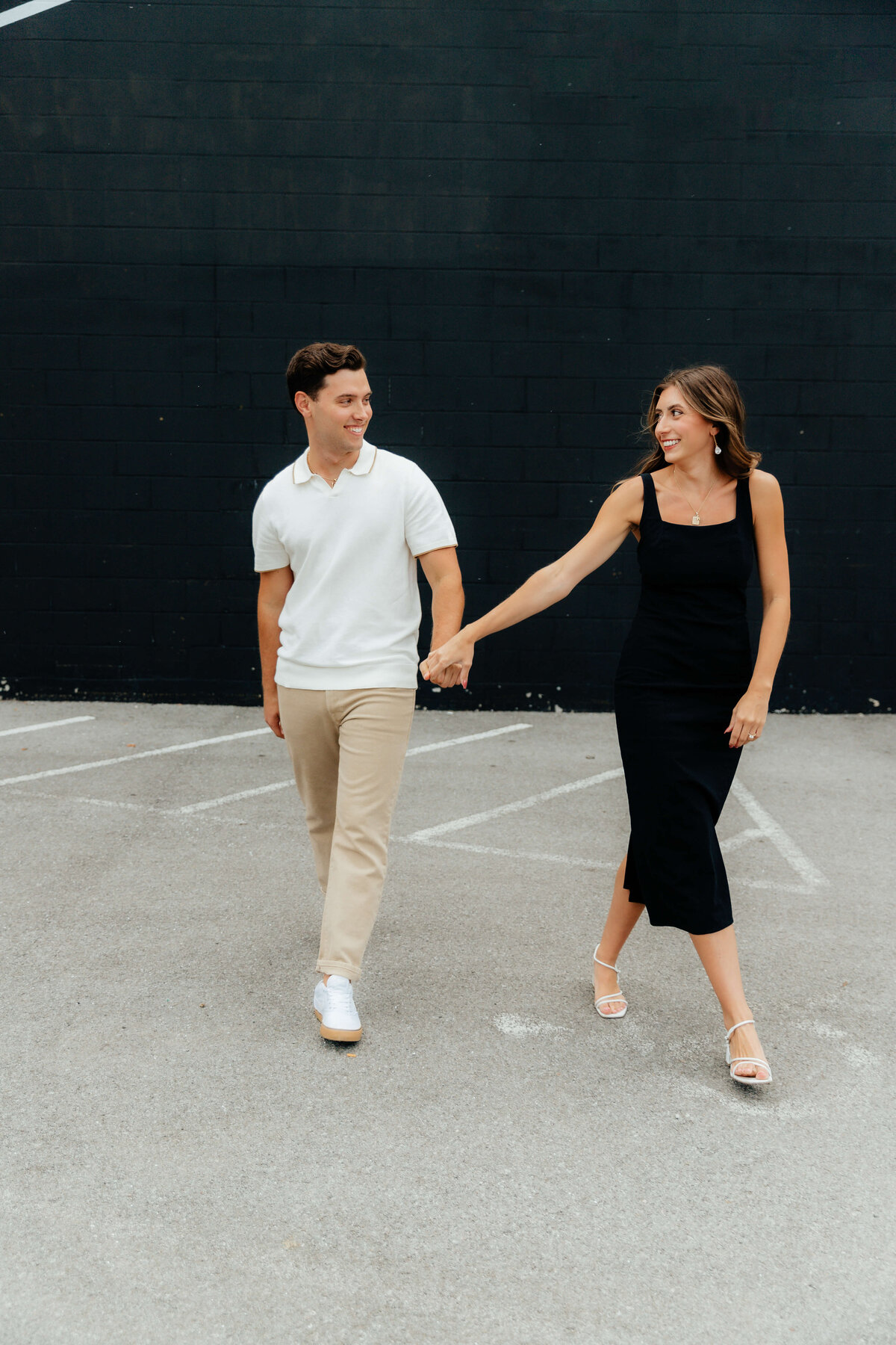 Modern couple walking hand-in-hand in parking lot, candid Ohio engagement photos for laid-back, style-forward Midwest couples in love