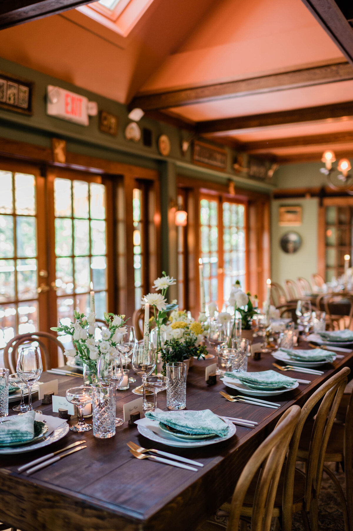 A detailed view of a place setting featuring a green-patterned napkin on a ceramic plate, paired with gold flatware and crystal glassware.