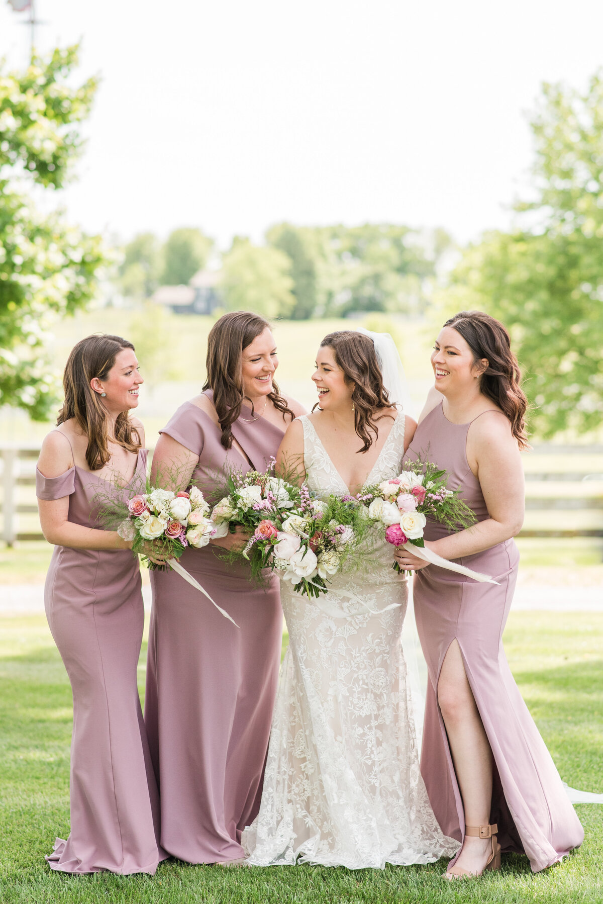 bridesmaids and bride smiling in mauve dresses