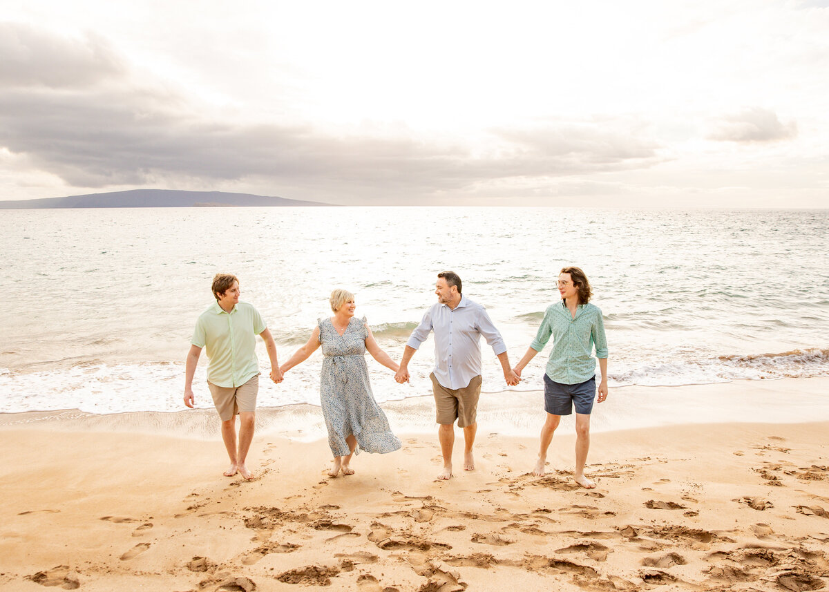 Maui Family Photographers capture family holding hands walking on beach during beach family photos