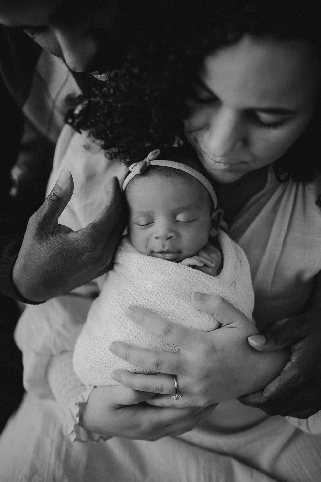 black and white image mother and father holding baby