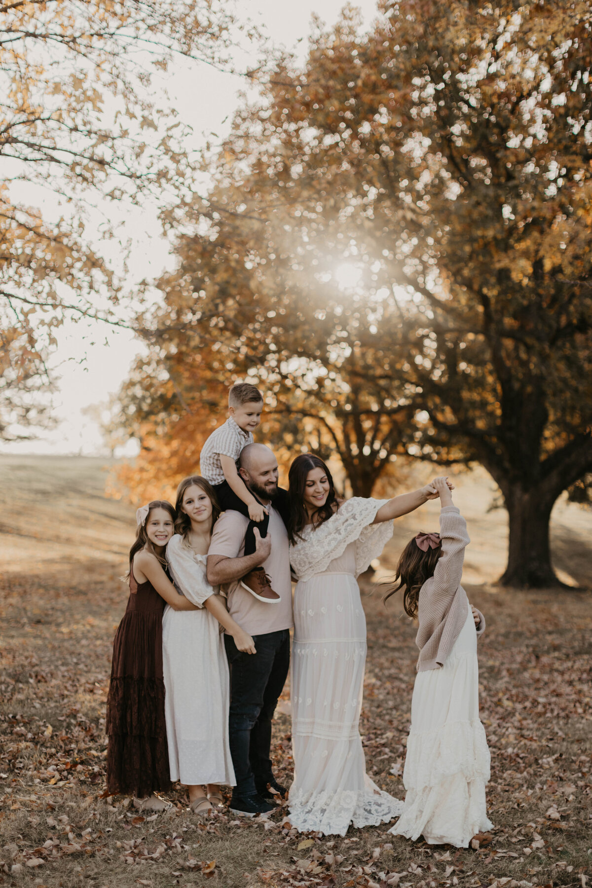 Family of 6 in close embrace with one daughter spinning in circles. 