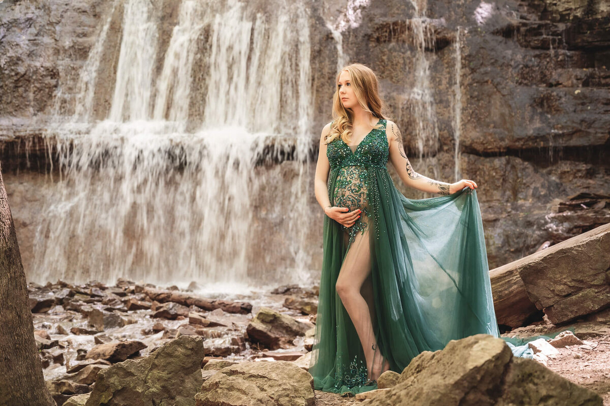 Glamorous maternity portrait posing in front of Sherman Falls in a green gown located in Hamilton, ON by Tamara Danielle Photography.