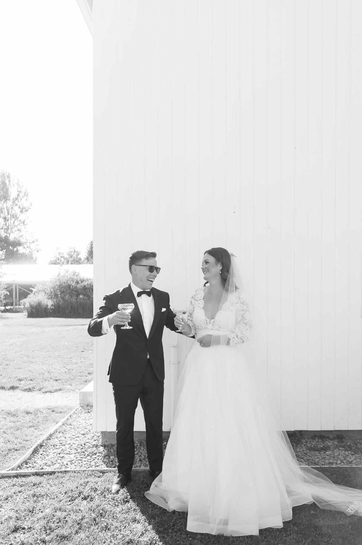 Black and white photo of a bride and groom popping champagne after their ceremony