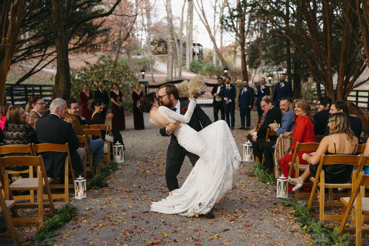 Bride and Groom doing a dip kiss walking back up the aisle after being pronounced husband and wife surrounded by fall mountains in North Carolina