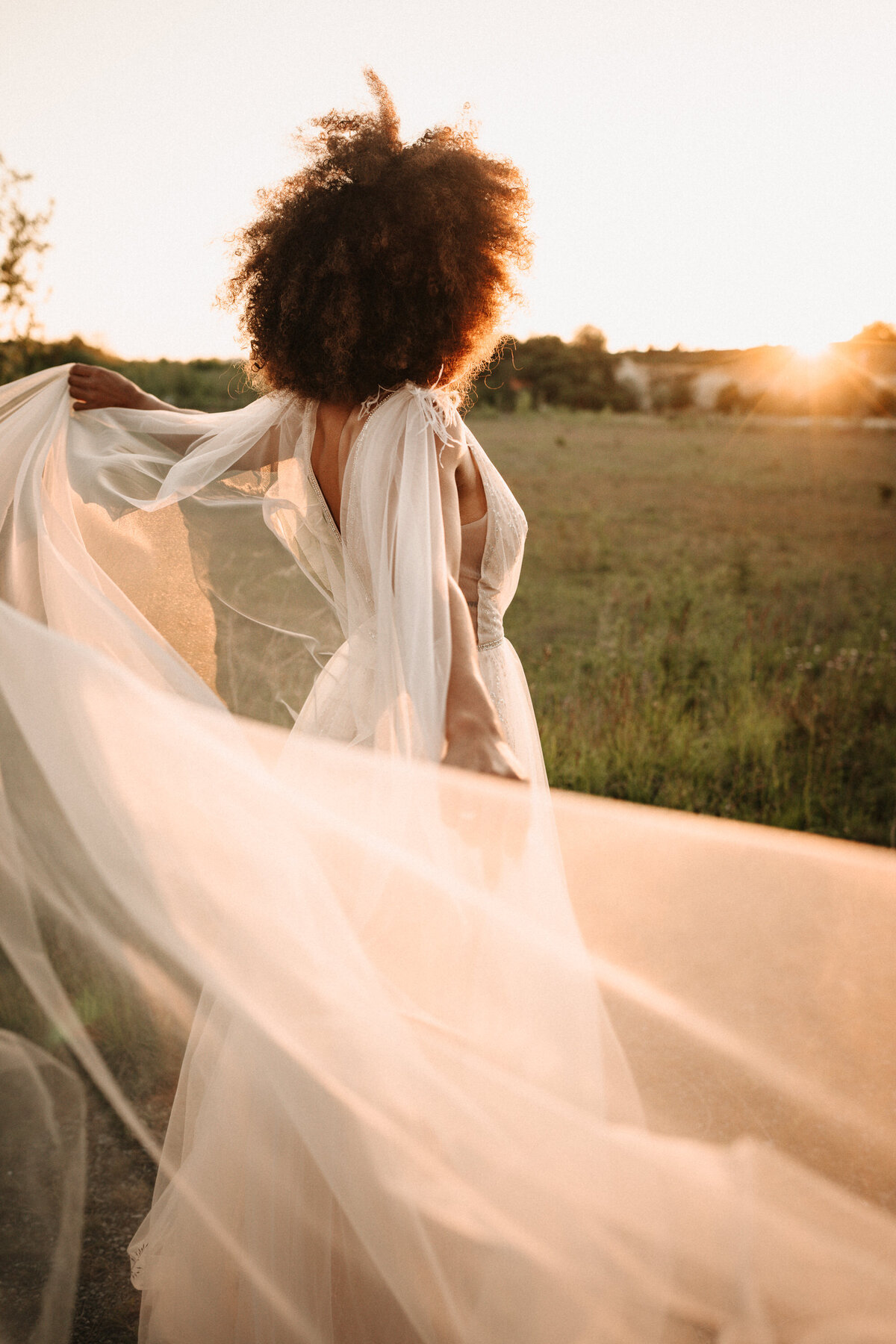 Braut mit langem Schleier im Sonnenuntergang