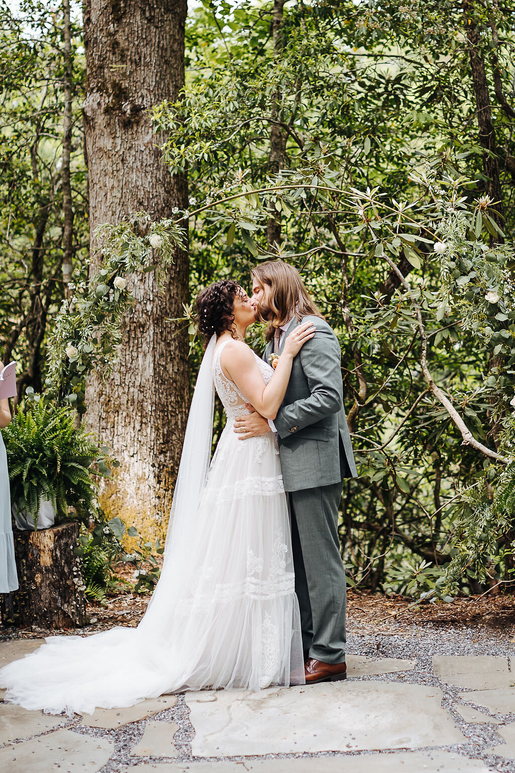 bride and groom kissing under trees