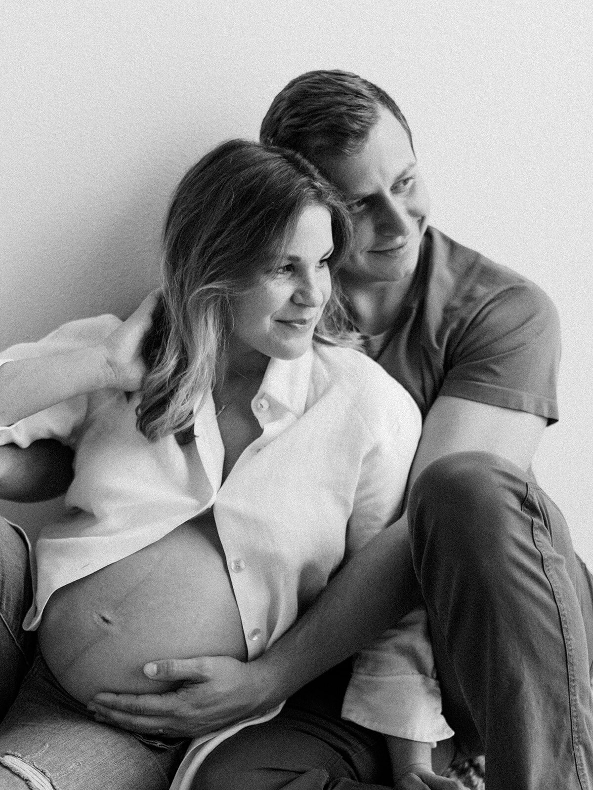 Black and white photo of husband holding his wife's pregnant belly