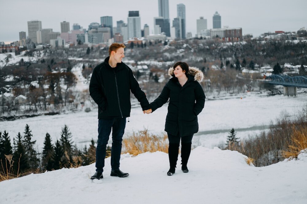 Edmonton couple hold hands in their black winter coats with snow on the ground