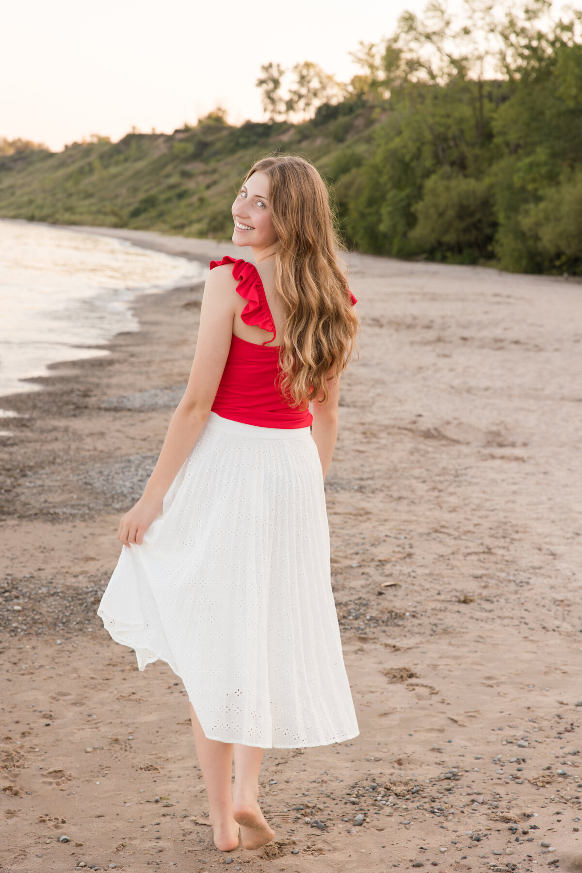 Senior girl on a beach looking over her shoulder and smiling at the camera