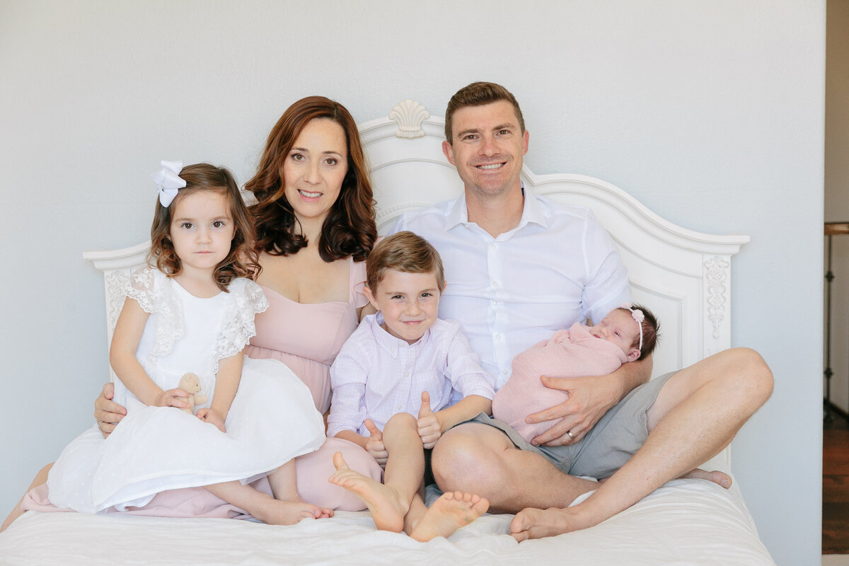 A family of five sitting on a bed together