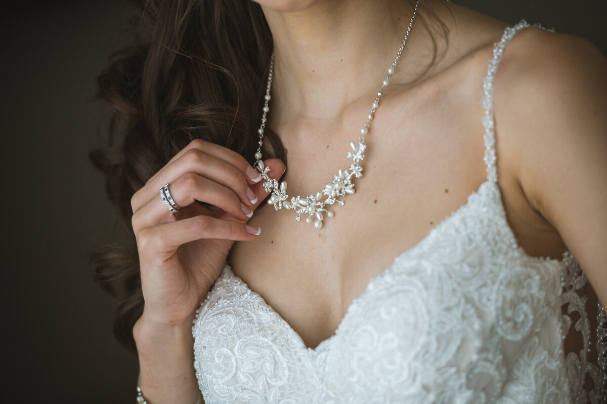 Bride hand holding wedding necklace.