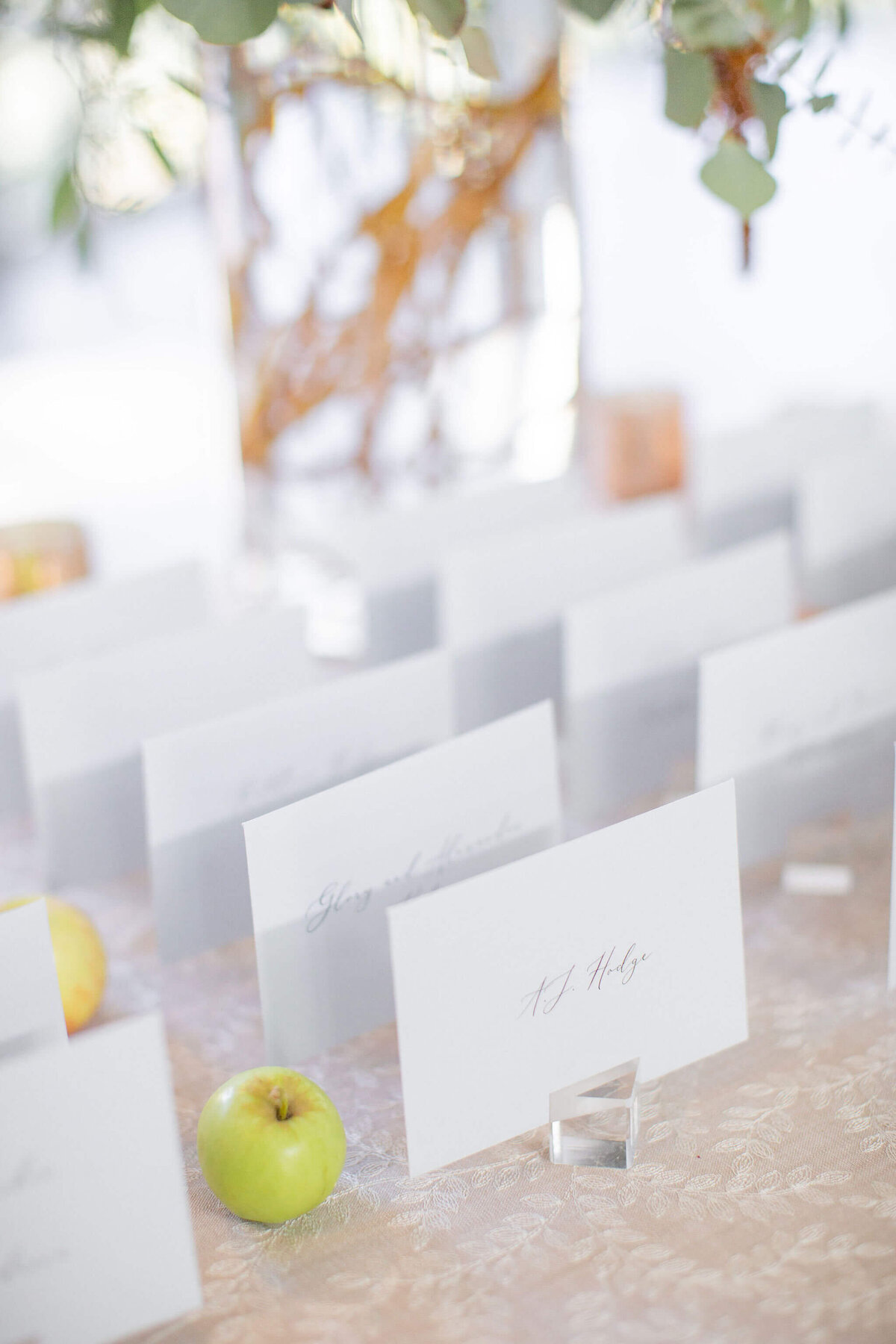 escort cards lined up on a table with large flower arrangement