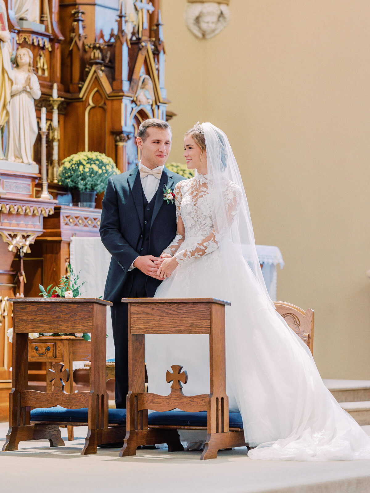 Bride and groom standing at altar and looking and smiling at one another during Catholic wedding Mass