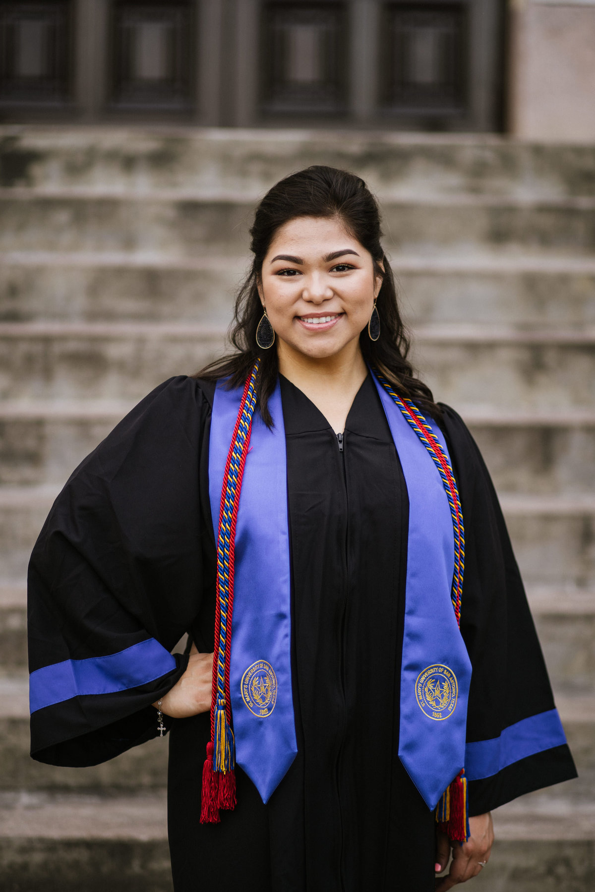 college senior posing with her cords and cap and gown by San Antonio senior photographer