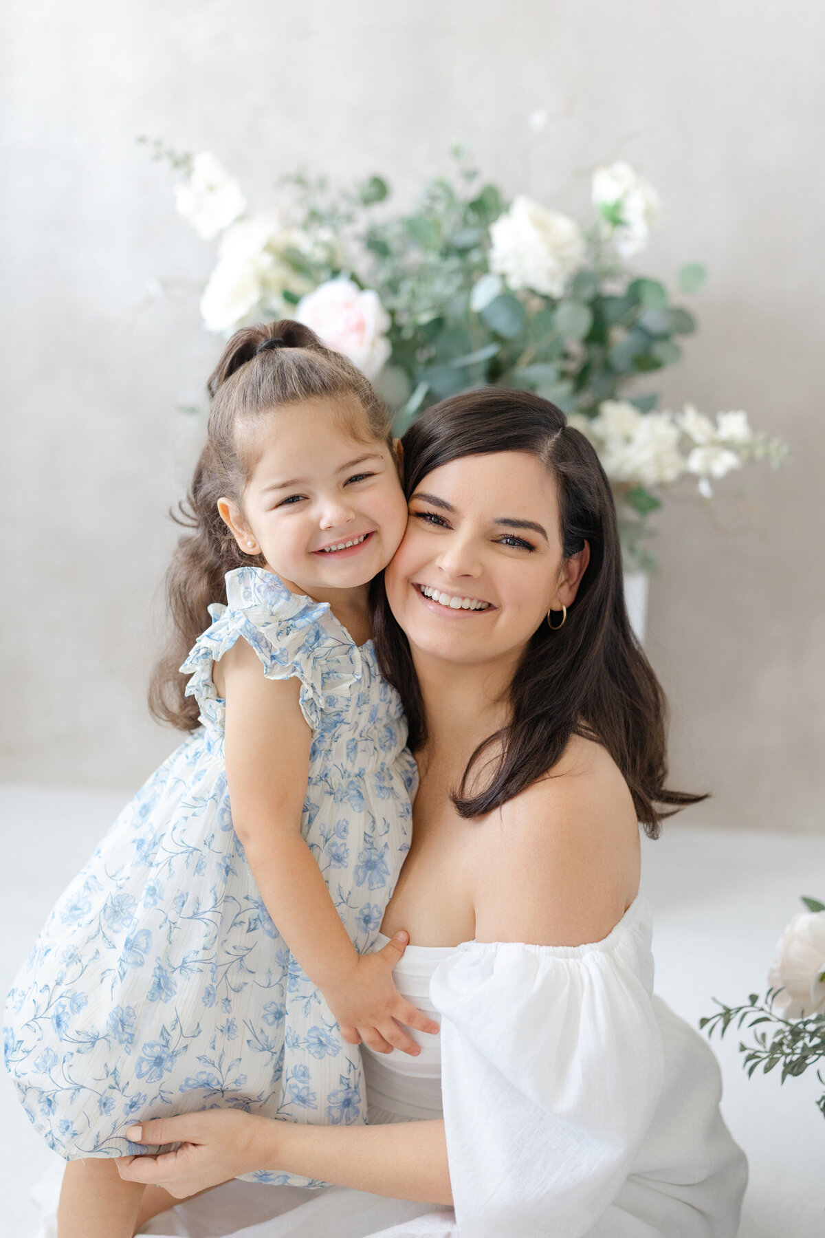 Joyful Tampa motherhood portrait of mom and daughter smiling together in soft natural light studio