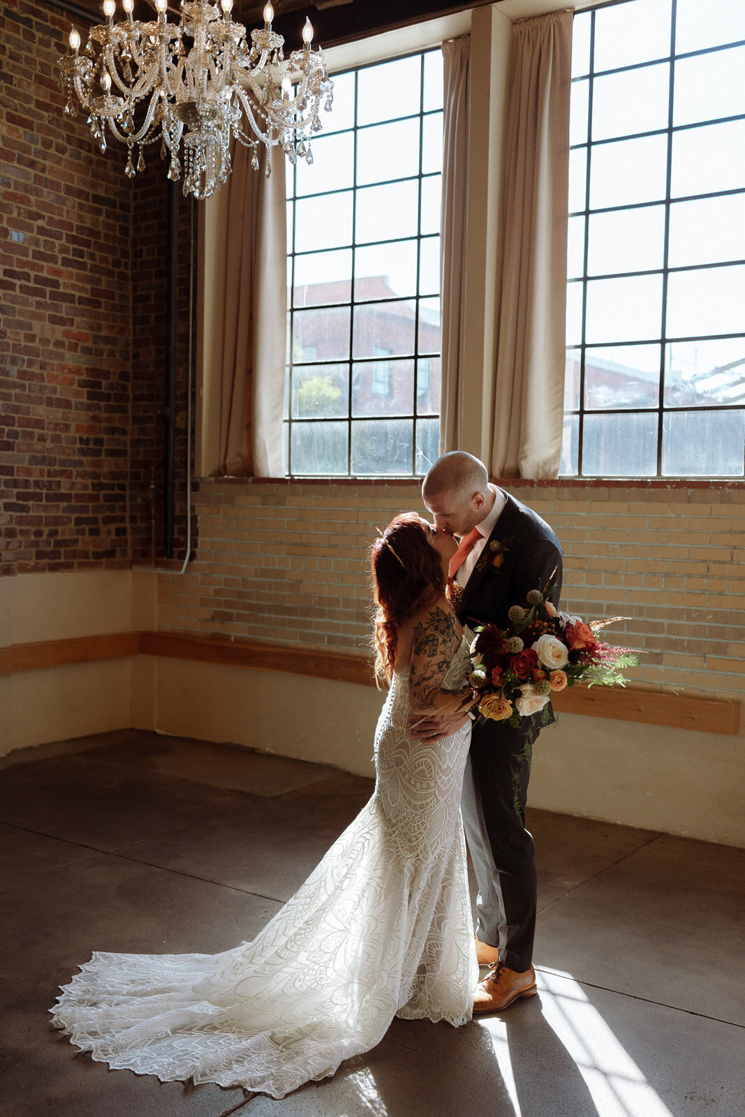 Bride and groom share a kiss  after their wedding ceremony at Upper Larimer  with a fall floral bouquet.