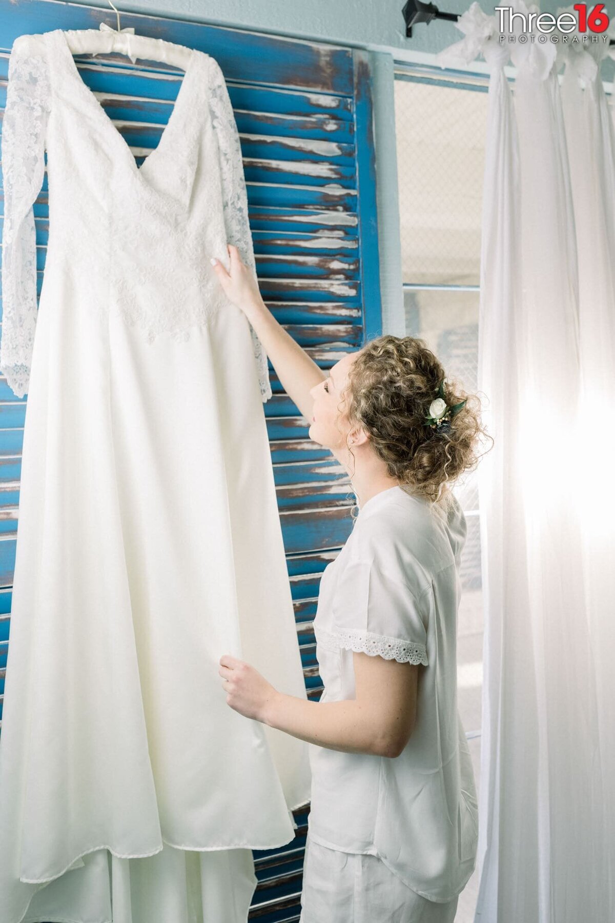 Bride looks at her wedding dress as it hangs on display