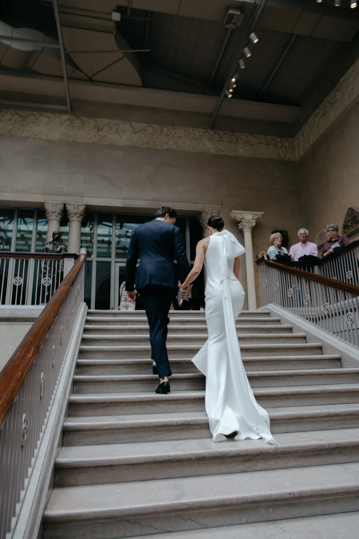 Wedding couple holding hands walking up stairs of Art Institute of Chicago
