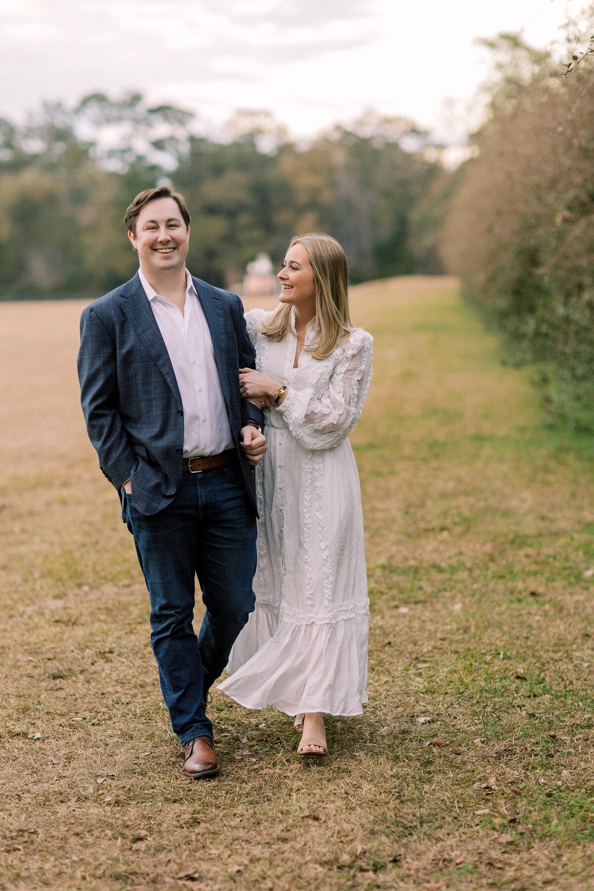 engaged couple smile while walking hand in hand