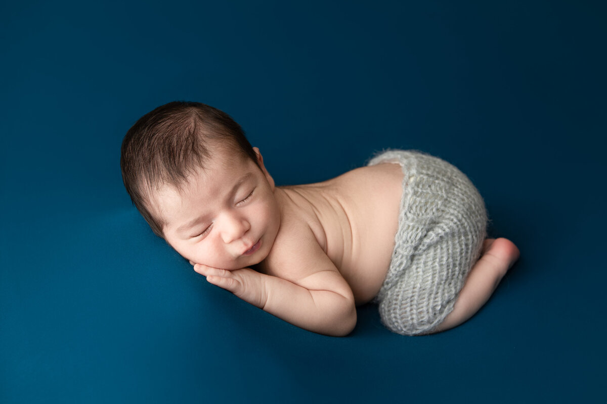 Studio table bum up pose on navy blue newborn boy