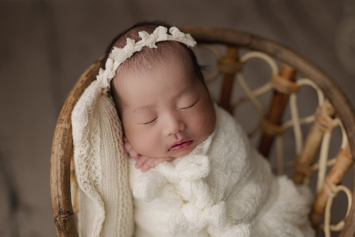 baby wrapped in white laying on small chair