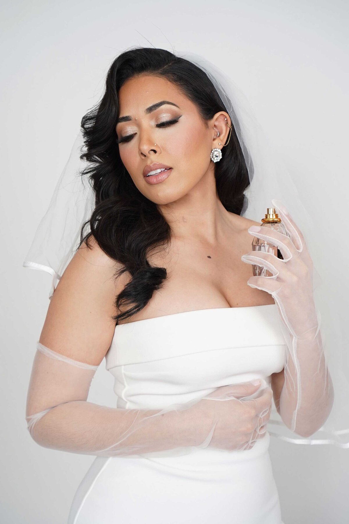 Beautiful bride in her civil wedding dress receiving bridal makeup services at a professional beauty studio in NYC.

