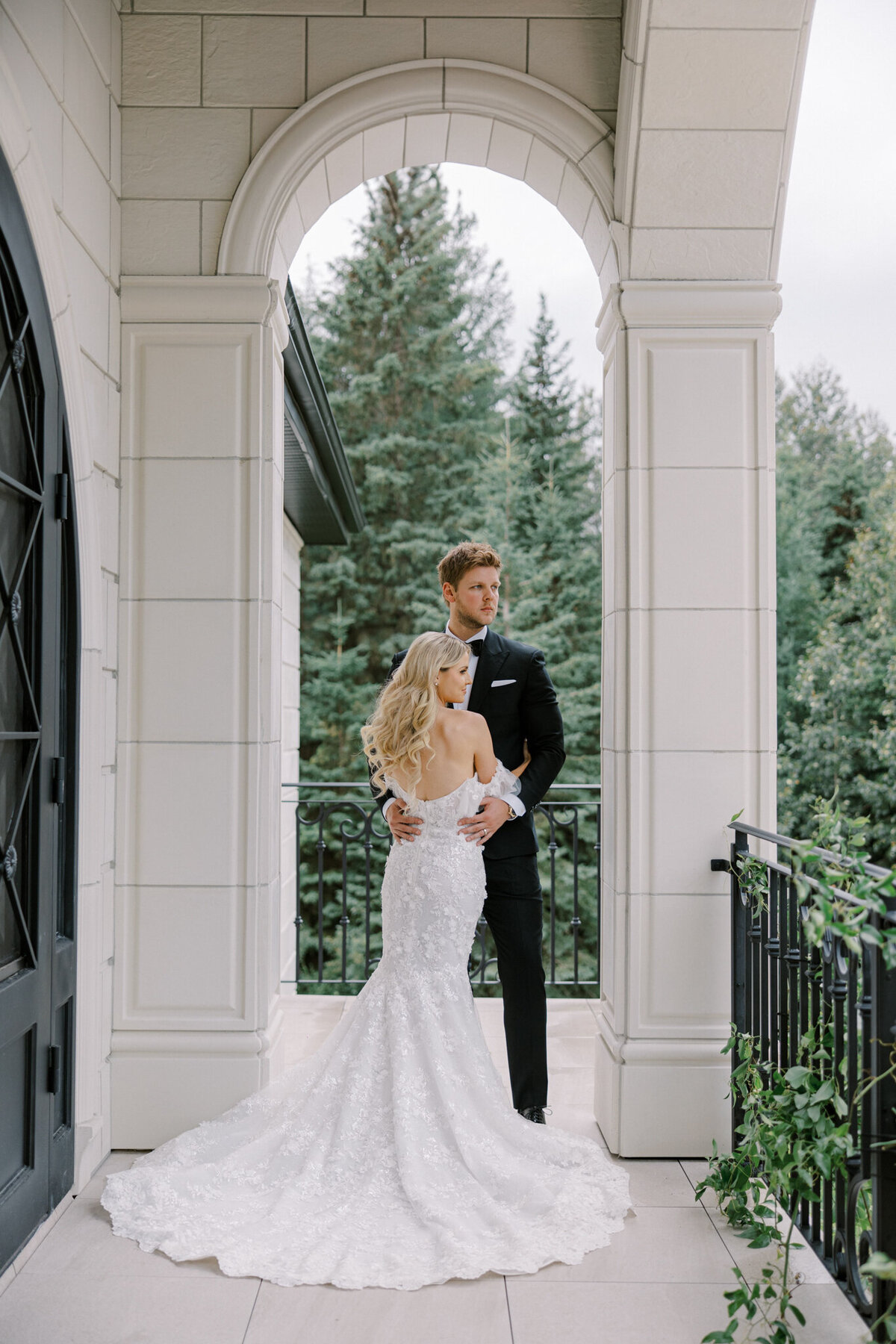 Couple standing in stunning arch at Archway Manor Weddings & Events, elegant, timeless, European-inspired Red Deer, Alberta wedding venue, featured on the Brontë Bride Vendor Guide.
