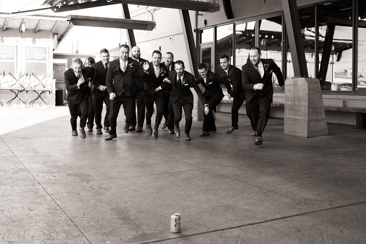 Groomsmen running to beer can wedding photo black and white Hagemeister Park Green Bay