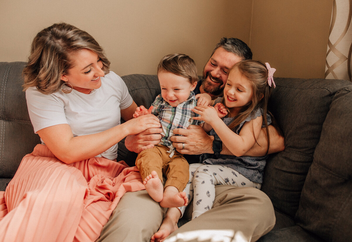 Family plays together while sitting on a couch.