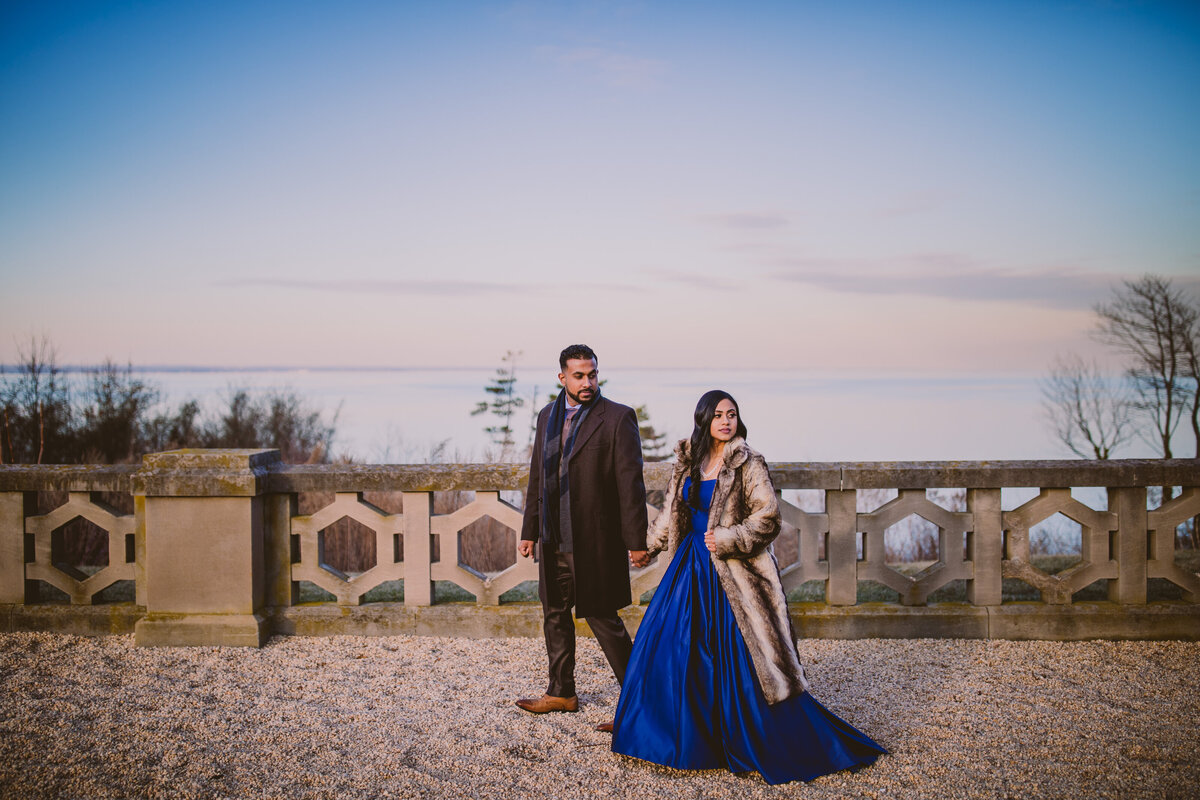 Bride and groom in formal outfits and coats walking outside in the garden at hempstead house at sands point preserve in ny