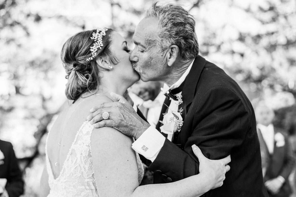 father of the bride kissing bride