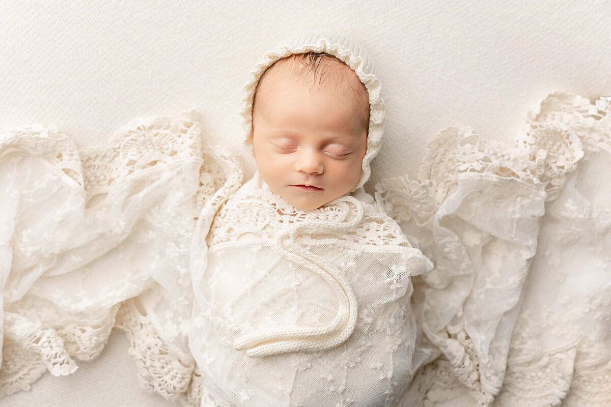 baby girl sleeping with lace over her wearing hat
