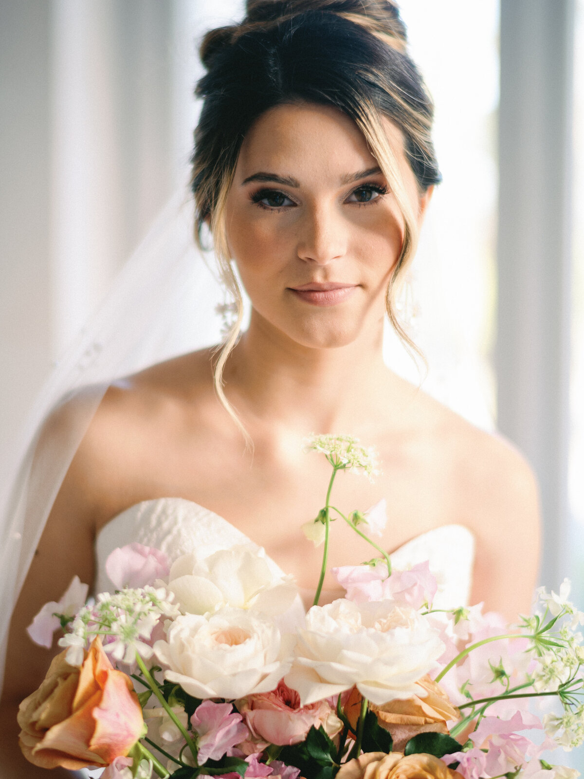 Fine Art bride posing by window with colorful garden party bouquet