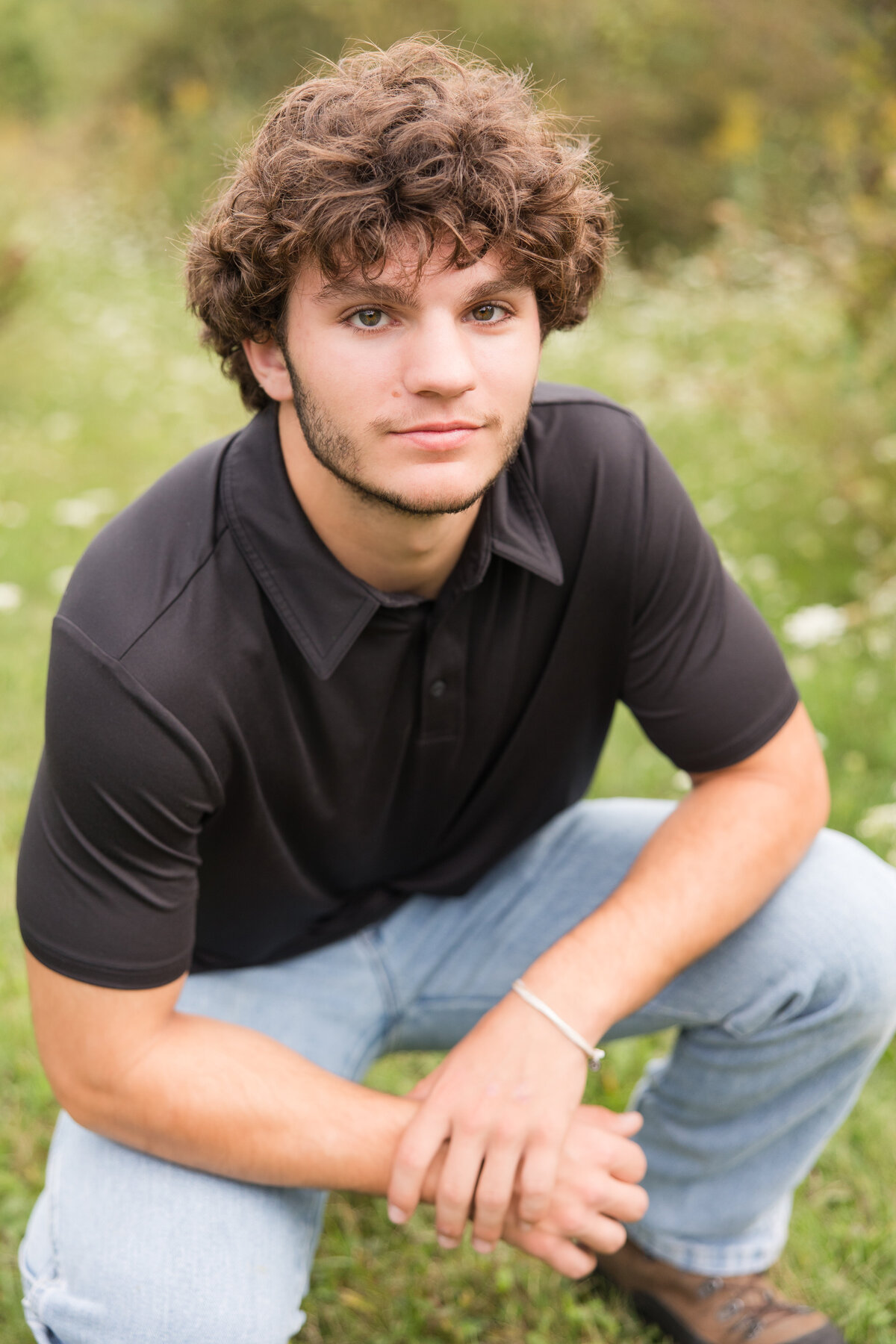 Senior guy squatting in a field looking at the camera