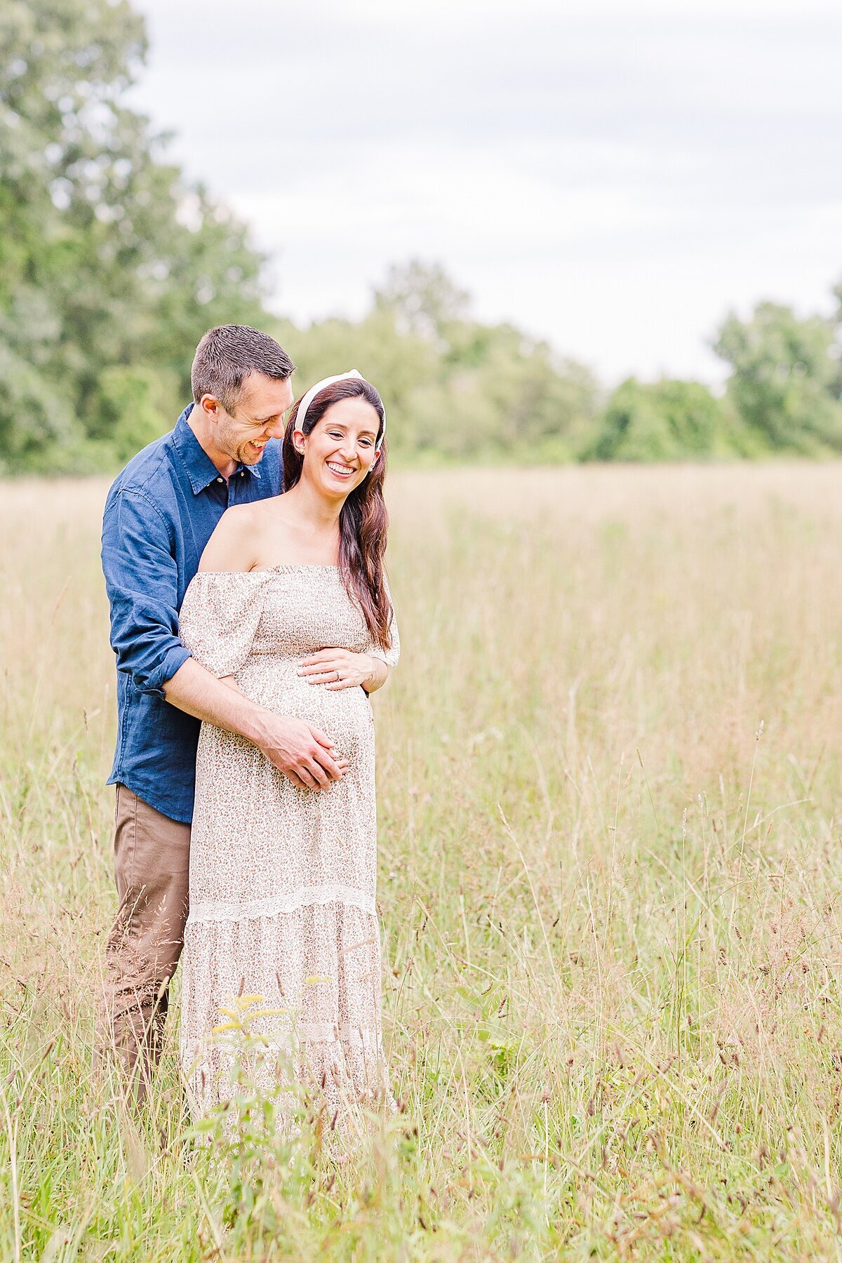 couple stands in filed of tall grass during maternity photo session with Sara Sniderman Photography at Heard Farm in Wayland Massachusetts