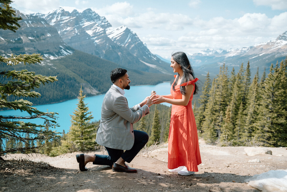 Scenic mountain proposal at Peyto Lake with bride-to-be in red dress overlooking the lake.