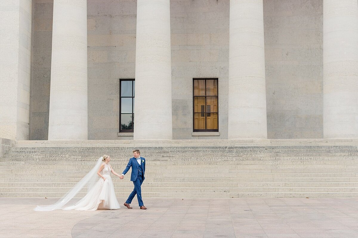 Groom leads bride walking in front of Ohio State House wedding taken by Ohio Wedding Photographer